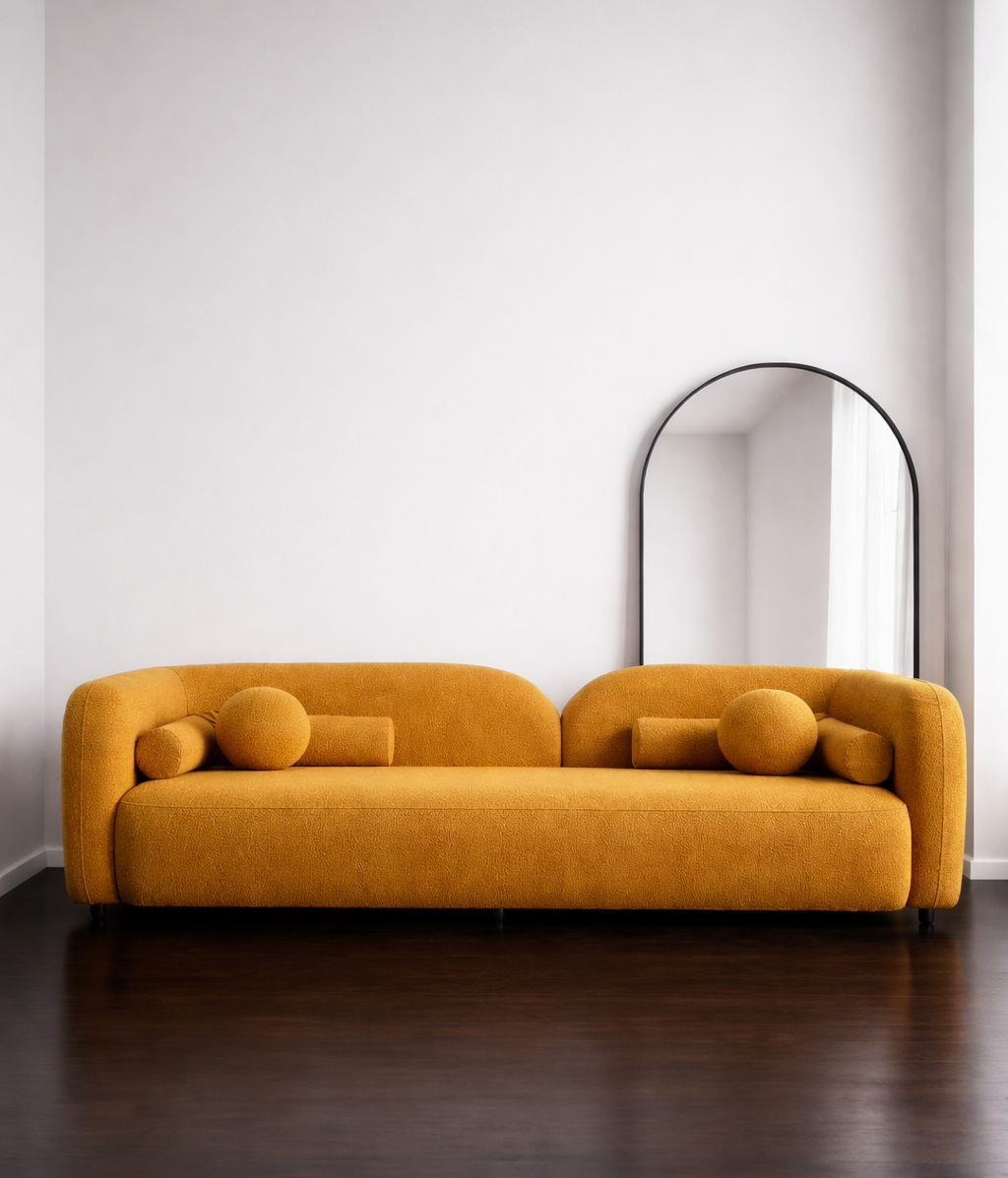 Mustard yellow sofa in a minimalistic room with a mirror on the wall.