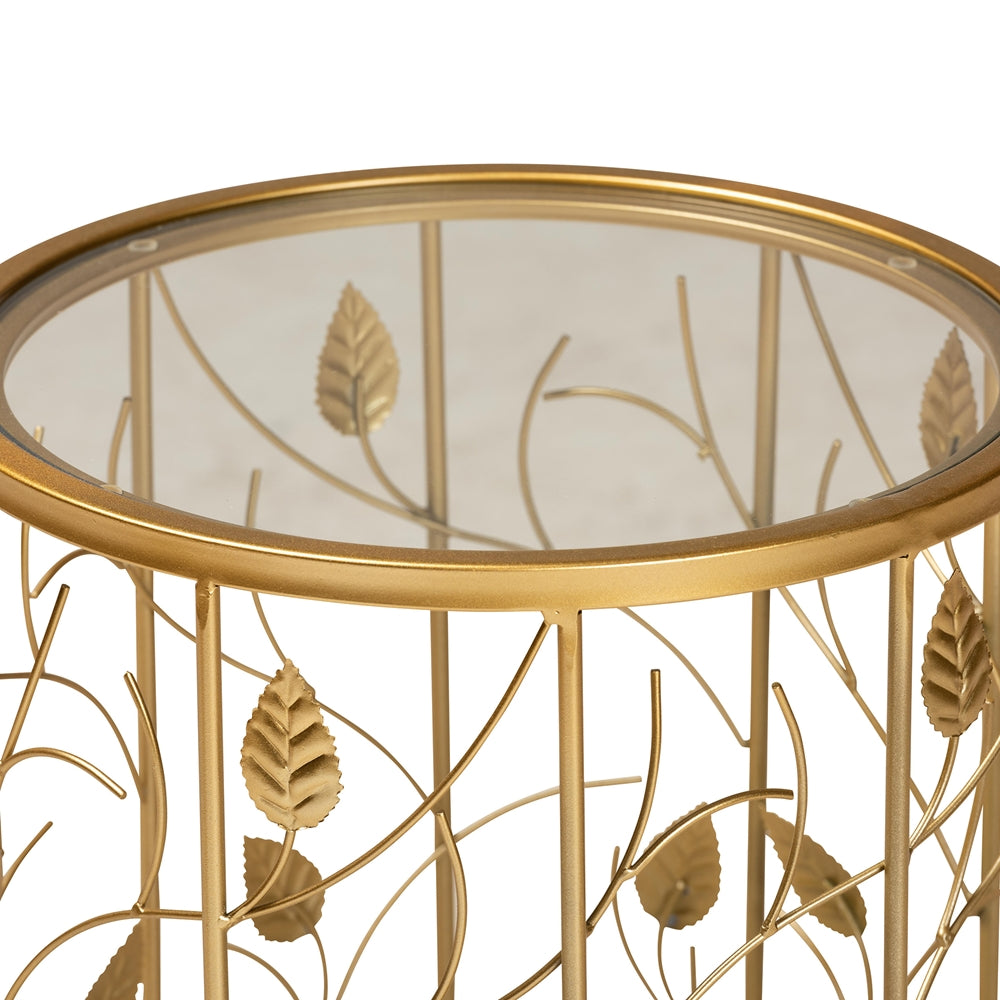 Gold leaf-patterned side table with glass top on a white background