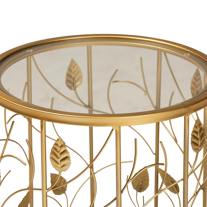 Gold leaf-patterned side table with glass top on a white background
