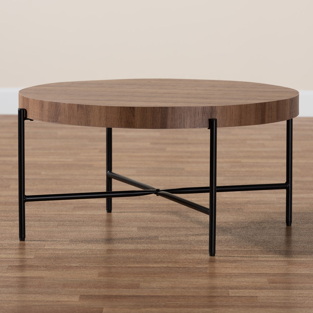 Round wooden coffee table with black metal legs on a wooden floor.