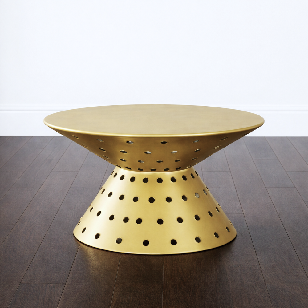 Gold metal side table with perforated design on a wooden floor.