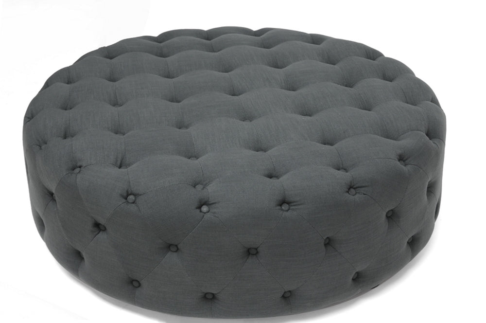 Gray tufted ottoman on a white background