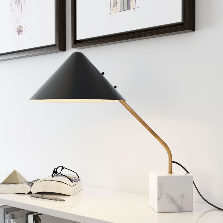 Modern desk lamp on a white surface with books and decor items.