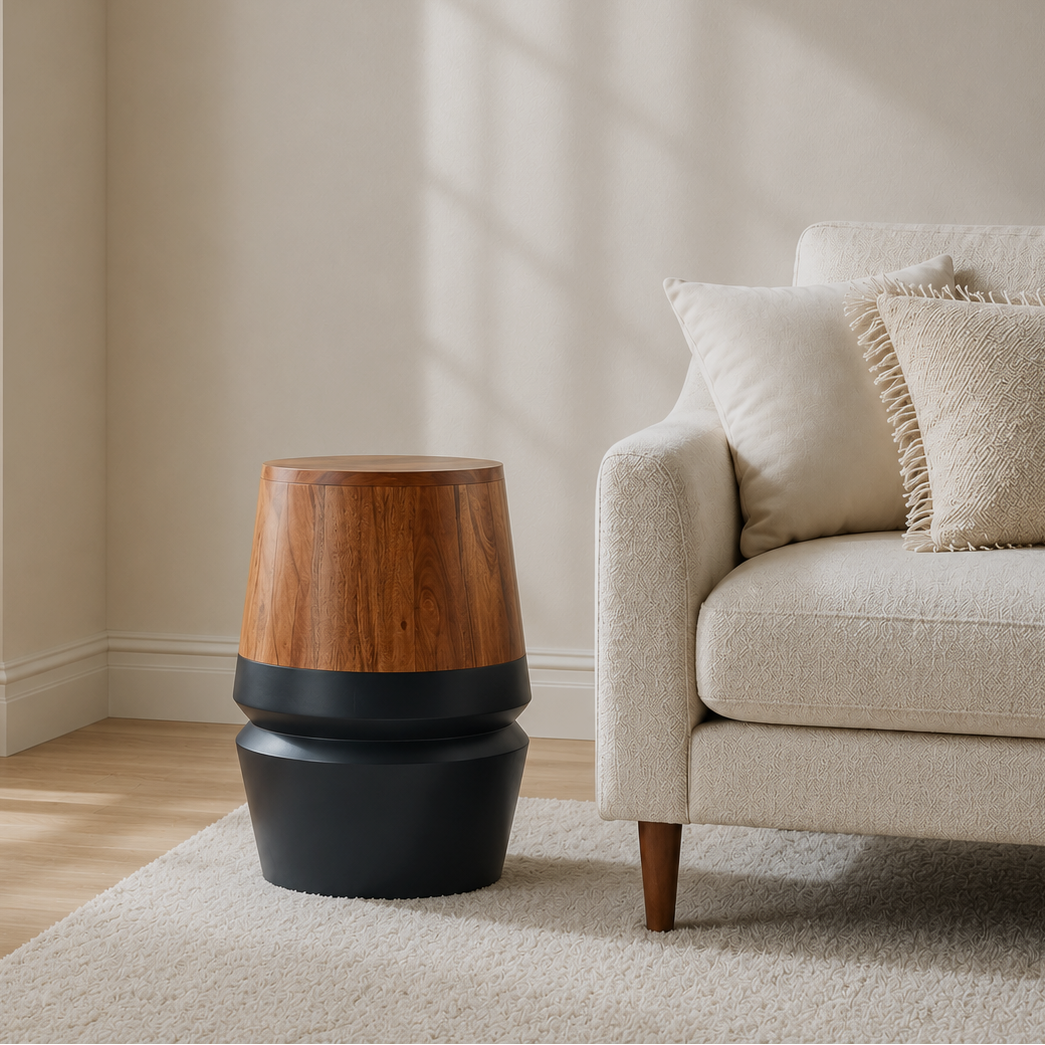 A modern side table with a stacked design, featuring a warm wood-grain top and matte black lower tiers, styled in a bright, minimalist living room next to a cream-colored sofa.