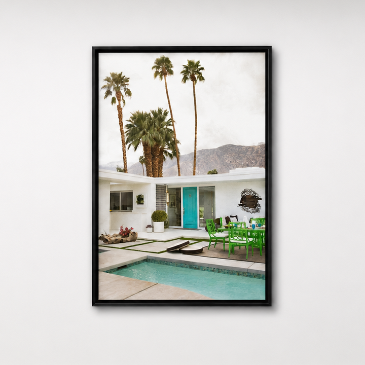 Framed artwork of a house with palm trees and a pool on a white wall. 