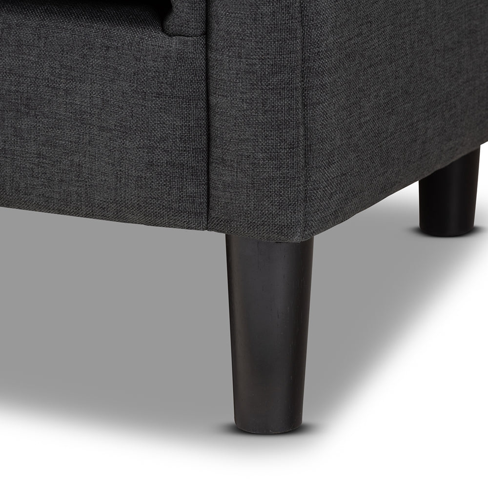 Close-up of a dark gray upholstered chair with black legs on a light gray background