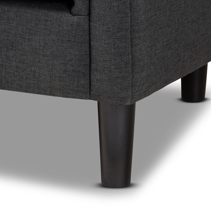 Close-up of a dark gray upholstered chair with black legs on a light gray background