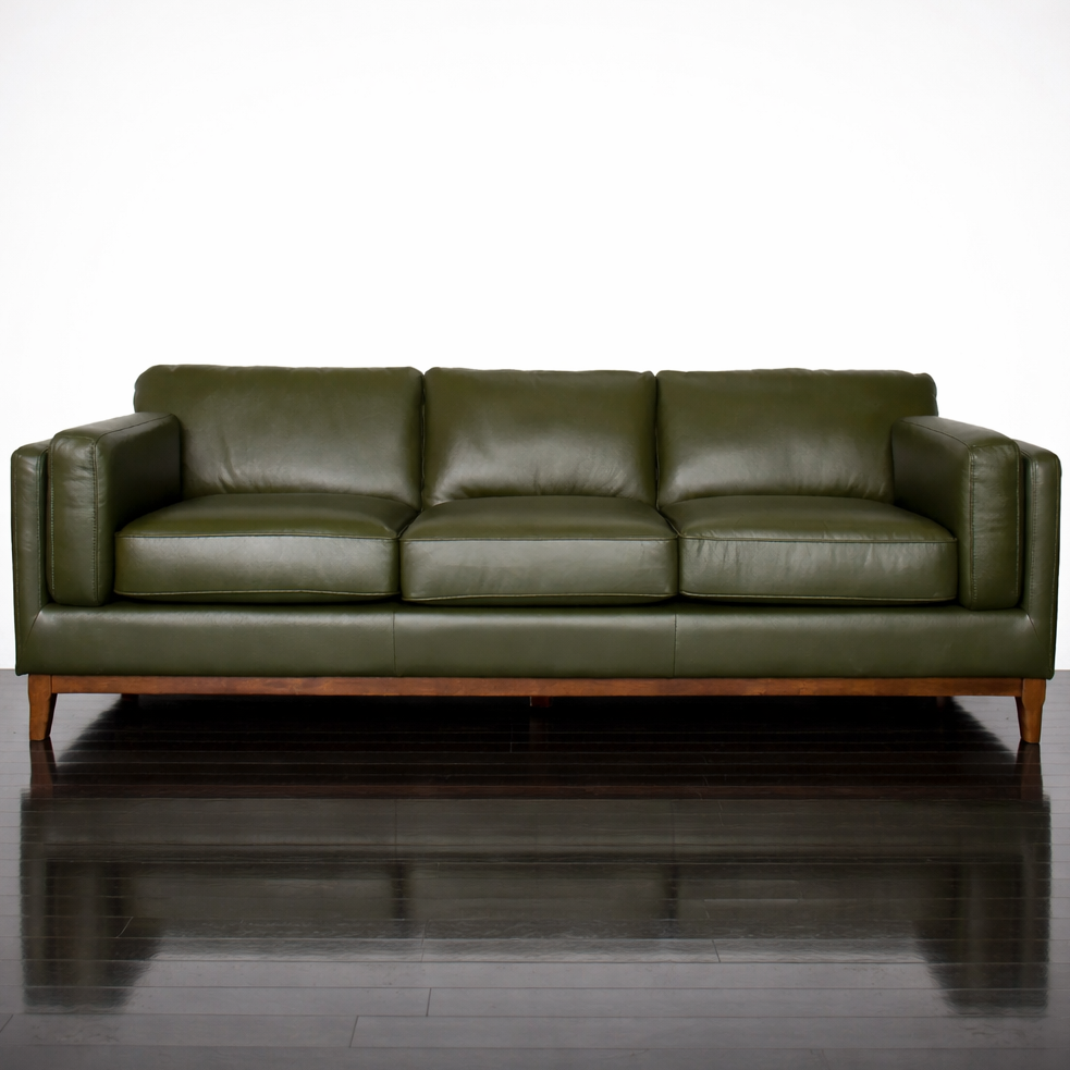Green leather sofa on a reflective surface with a white background