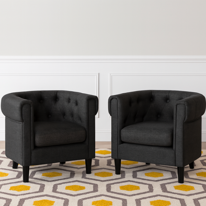 Two dark gray armchairs on a patterned rug with a white wall background