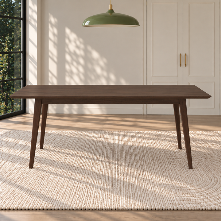 A dark brown wooden dining table with tapered legs, set on a textured cream woven rug in a bright, modern room with a green pendant light overhead.