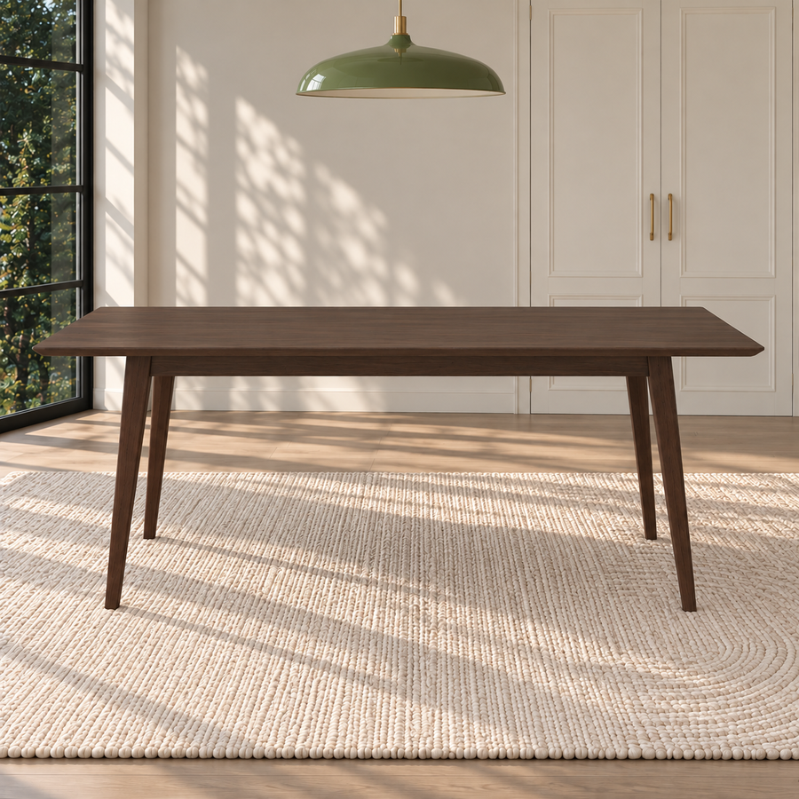 A dark brown wooden dining table with tapered legs, set on a textured cream woven rug in a bright, modern room with a green pendant light overhead.