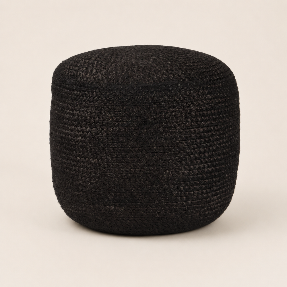 A round black woven pouf or ottoman with a textured, basket-like weave, photographed against a solid, warm off-white background.
