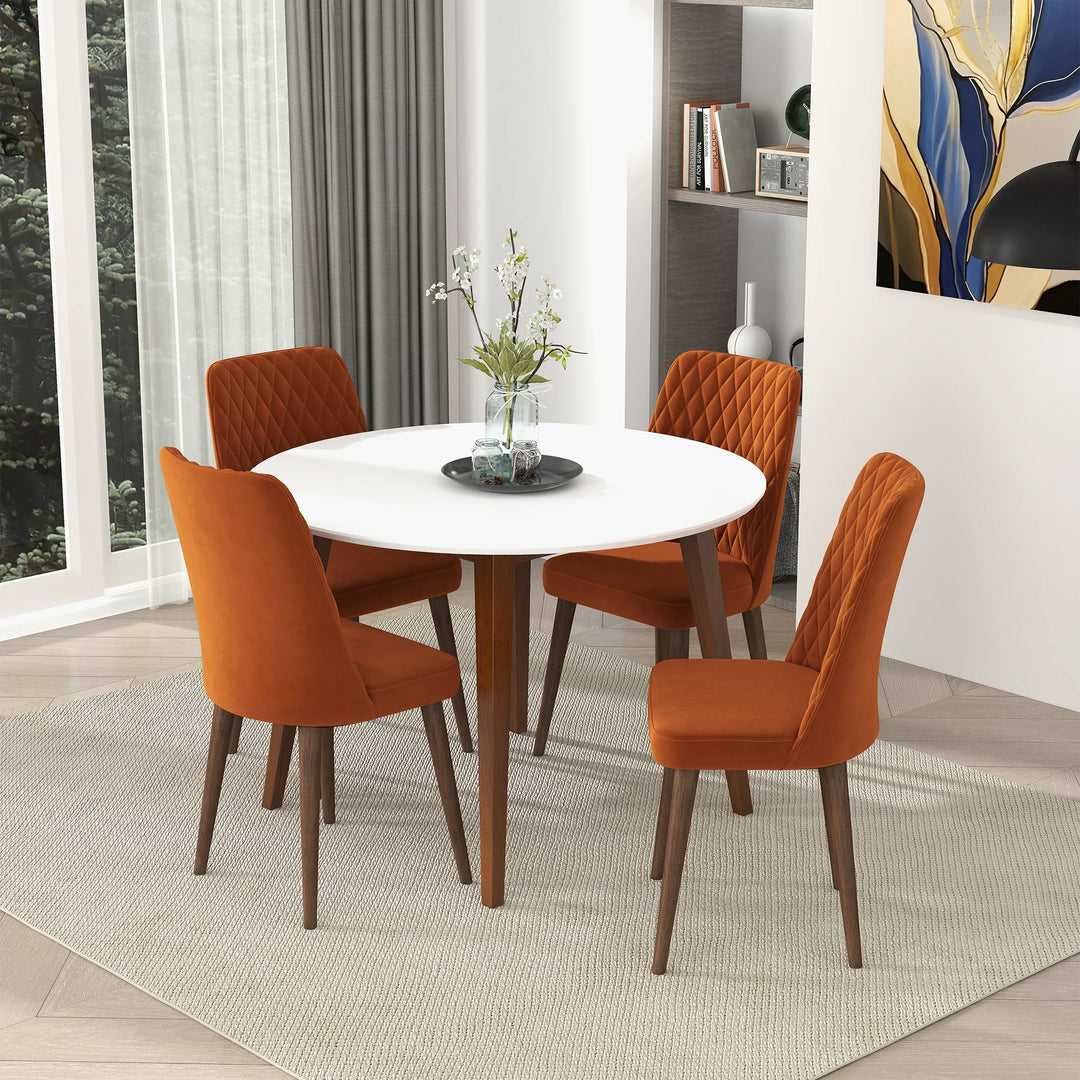 Dining room with a round white table and four orange chairs.