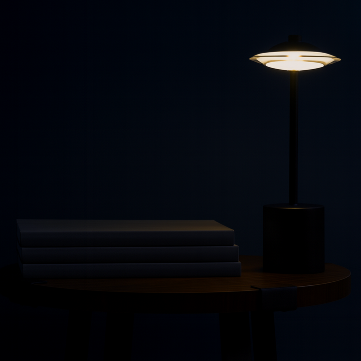Dark room with a lit table lamp casting light on stacked books.