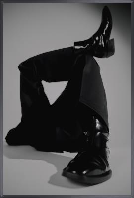 Black leather shoes and pants on a gray background