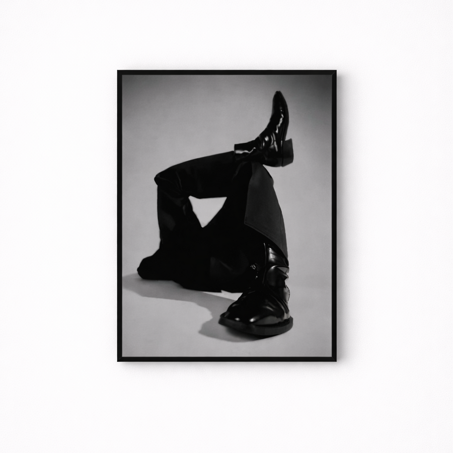 Framed black and white photo of a person wearing shiny black shoes on a white background