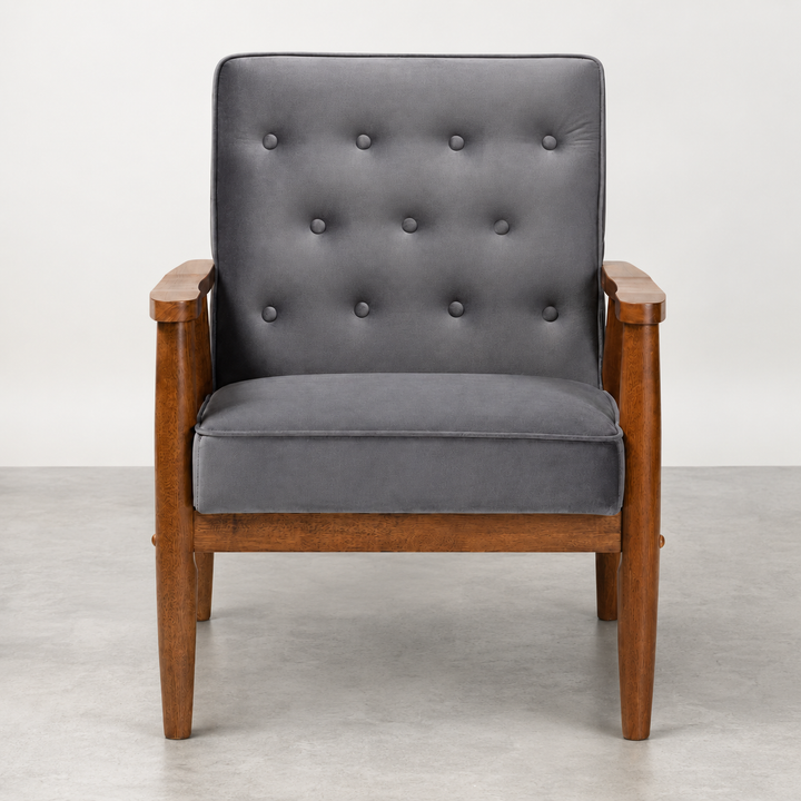 A mid-century modern armchair with a dark gray tufted velvet cushion and a warm brown wooden frame, shown against a neutral gray studio background.