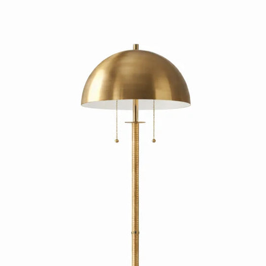 A modern floor lamp with a brushed brass dome shade, slim central stem, and round base, shown against a plain white background.
