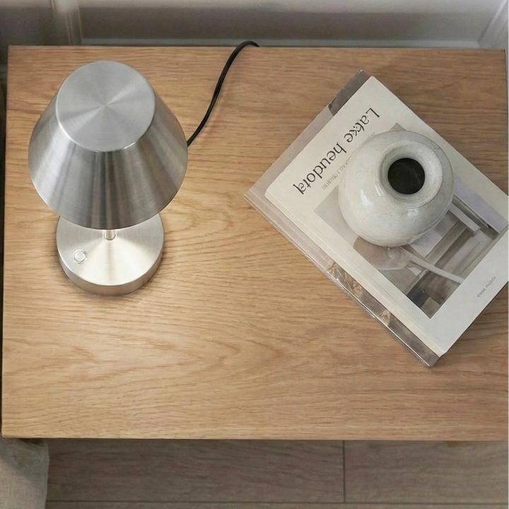 Silver lamp on a wooden side table next to a sofa 