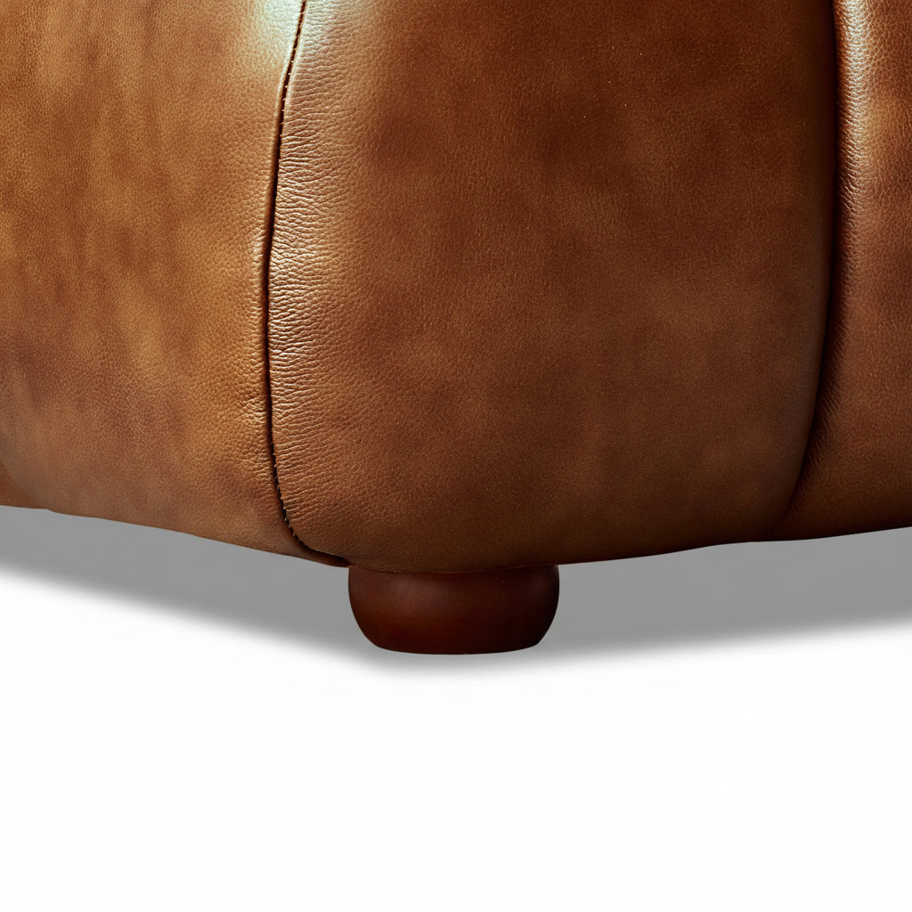 Close-up of a brown leather sofa on a wooden floor.