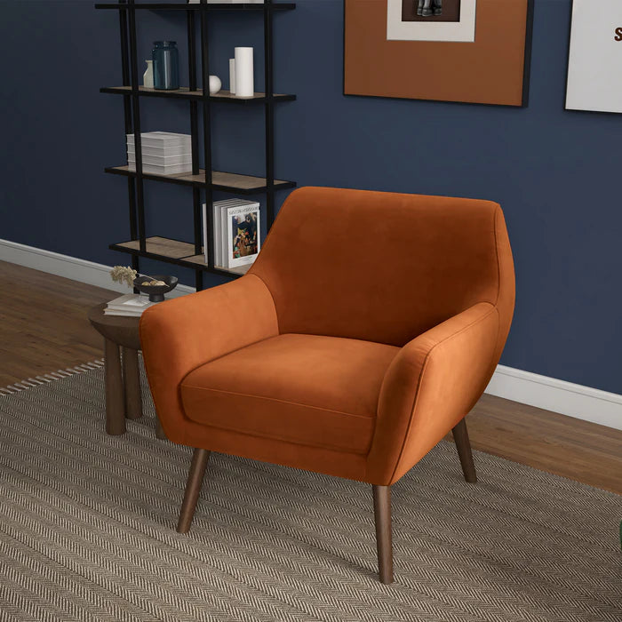 Orange armchair in a room with a bookshelf and framed picture on a blue wall.