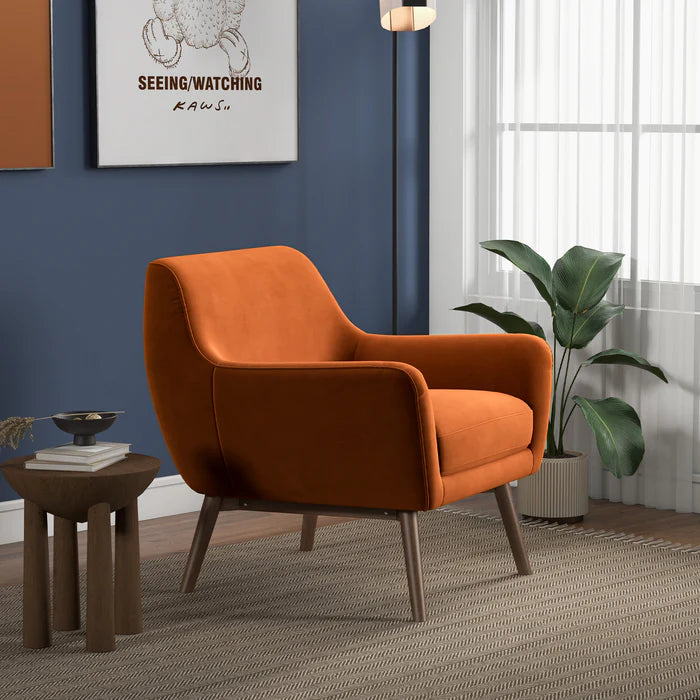 Orange armchair in a room with a blue wall, framed picture, and plant.
