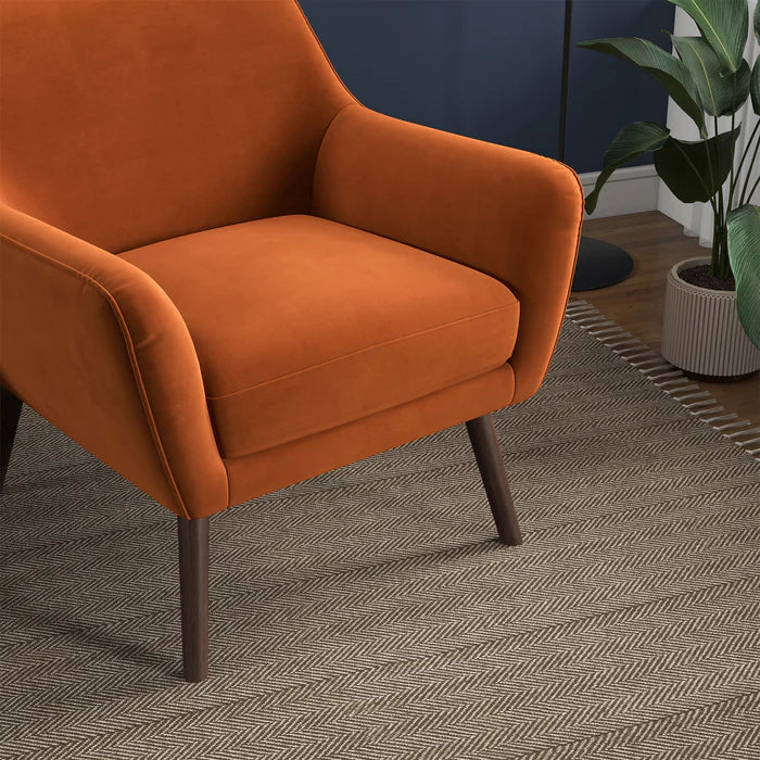 Orange armchair in a room with a plant and patterned rug