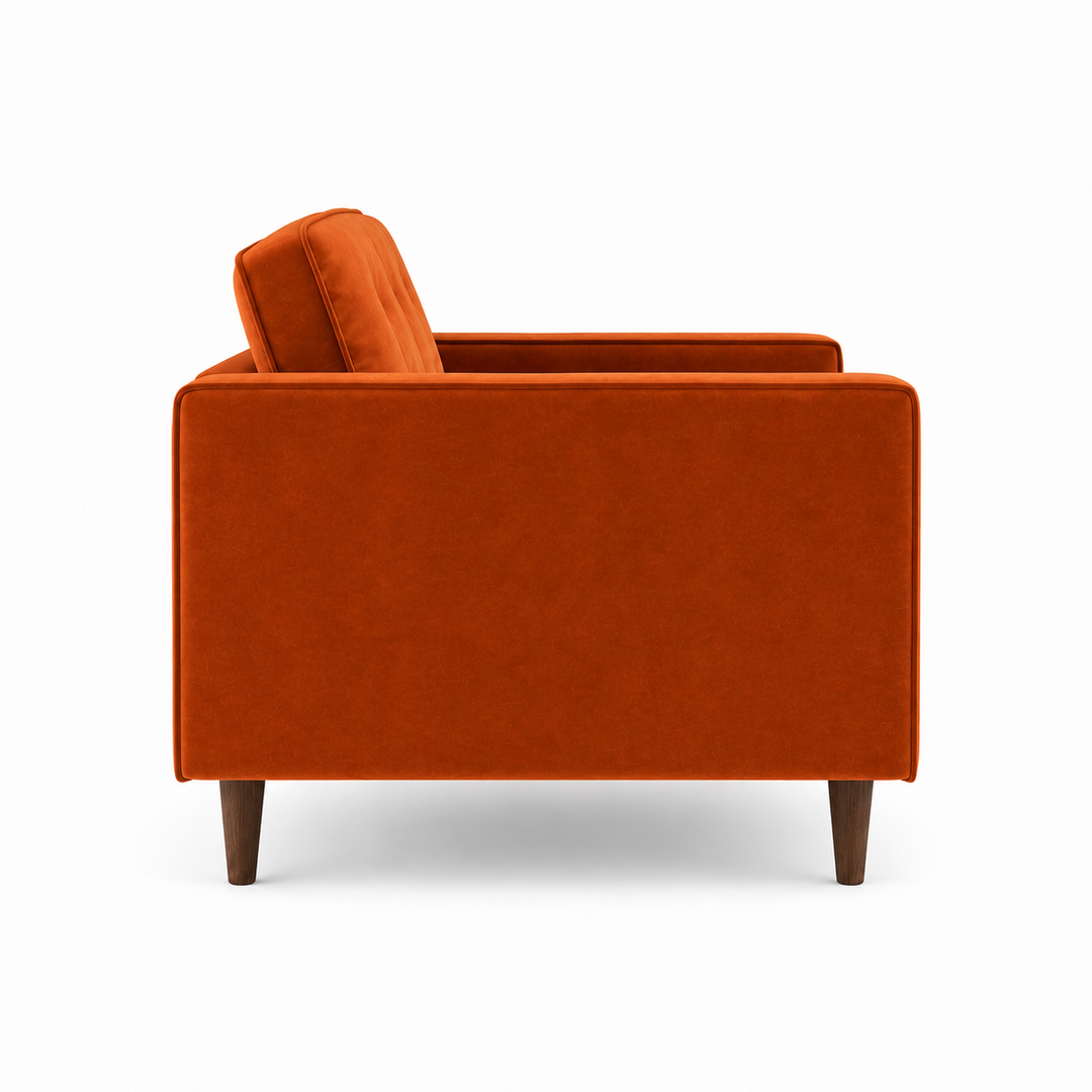 An orange velvet armchair with dark brown wooden legs, shown from a three-quarters angle against a plain white background.