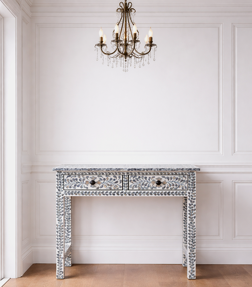 Decorative console table with intricate designs in a room with white walls and wooden flooring.