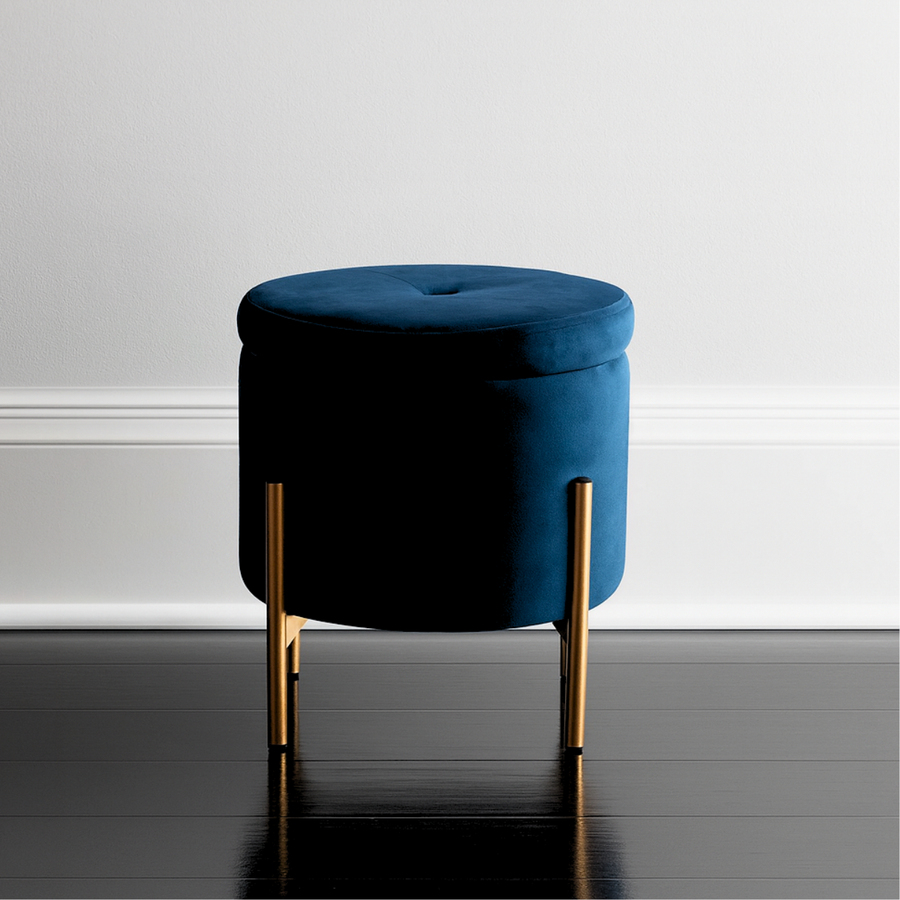 Blue ottoman with gold legs on a gray floor against a white wall