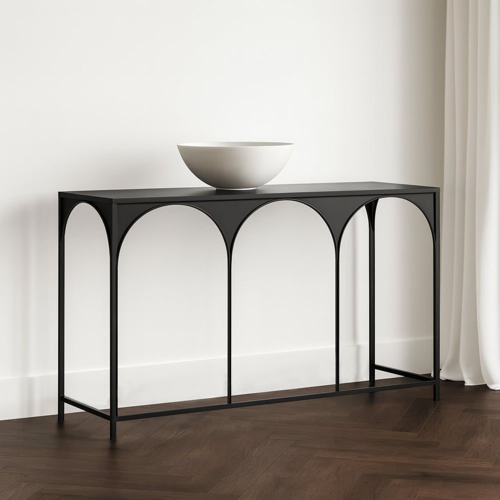 Console table with arch designs on a wooden floor against a white wall