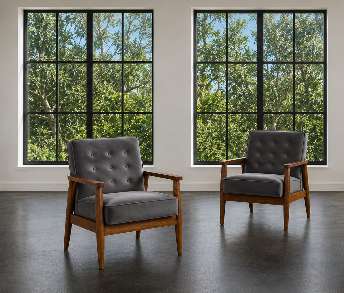 Three mid-century modern armchairs with gray tufted upholstery and wooden frames, arranged in a spacious room with large black-framed windows showing green trees outside.