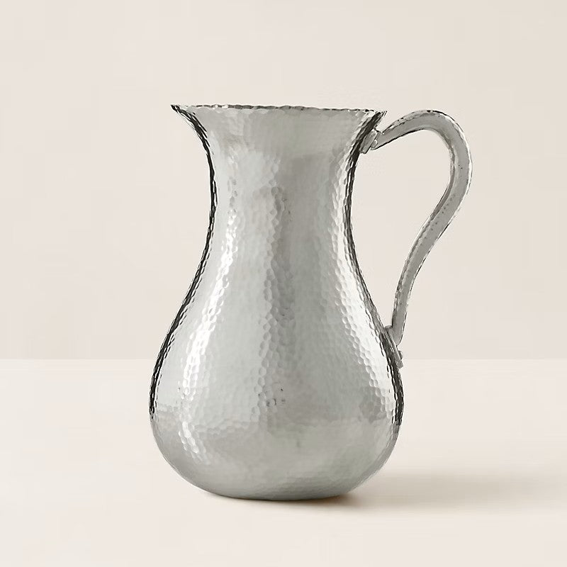 An artful hand-hammered technique creates the distinctive pebbled texture that defines our Evans pitcher. Made with brass, it features a lustrous nickel finish that highlights natural variations throughout.