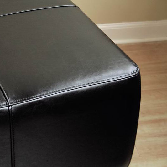 Black leather ottoman on a wooden floor